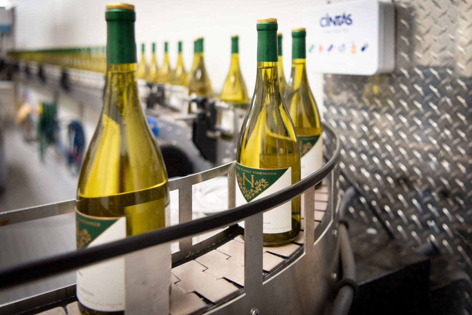 Naumes Family Vineyards wine bottles run through an automated bottling machine.